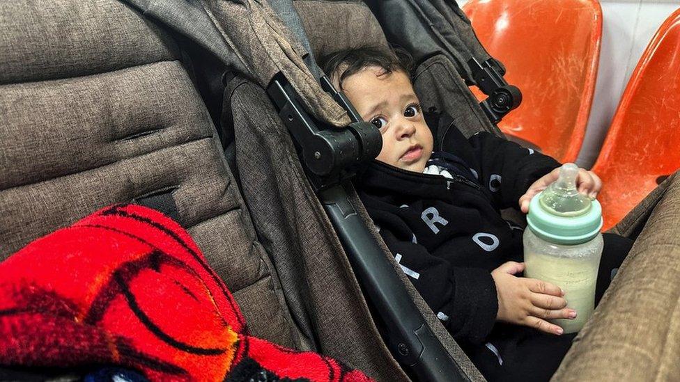 A Palestinian boy, who has a skin infection, looks on at a hospital in Rafah, in the southern Gaza Strip (12 December 2023)