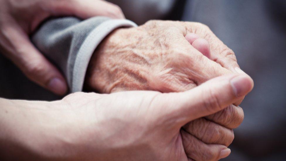 An older person's hand being help by a younger person.s