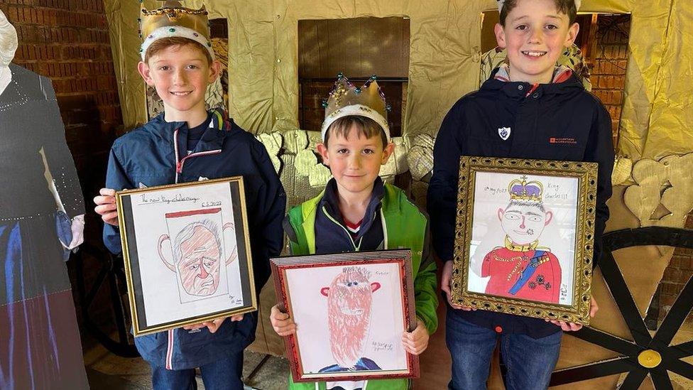 Three children holding pictures of the King.