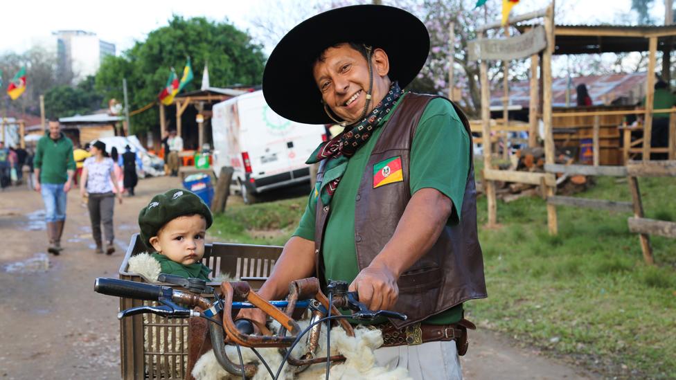 A gaúcho pushes a baby in a bike basket