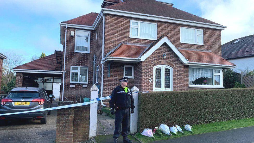 A police officer stands outside a house