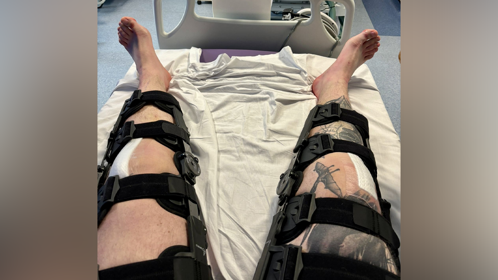 Dan Jones's legs strapped up in supports while he lies on a hospital bed