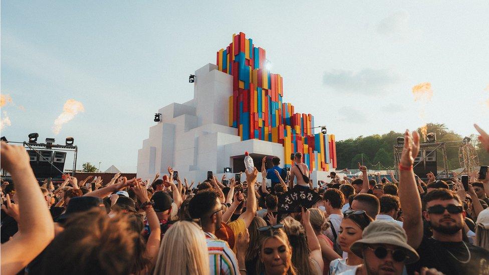 A crowd of people surrounding one of the main stages on a sunny day at Love Saves the Day festival