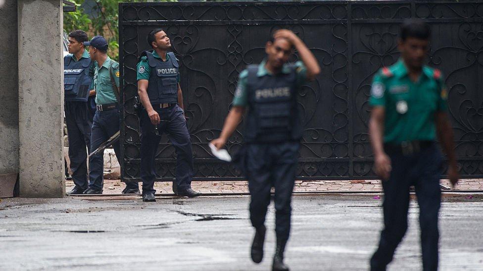 Bangladeshi policemen exit from a gate leading to an upscale cafe in Dhaka on July 03, 2016