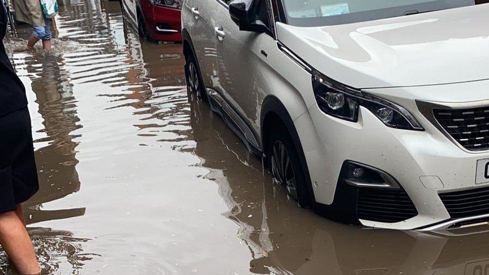 People wade through floods to return to their cars