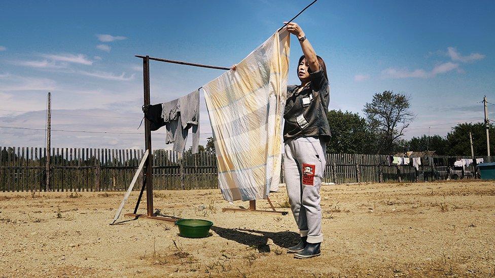 A Chinese woman hangs out the washing on a farm at Dimitrovo