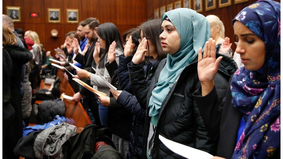 People take the oath of allegiance in a naturalisation ceremony