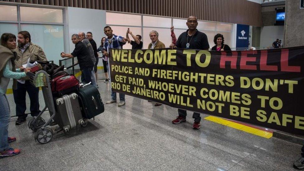 Police officers welcome passengers with a banner reading "Welcome to Hell" and other slogans as they protest against the government for delay in their salary payments at Tom Jobim International Airport in Rio de Janeiro, Brazil, July 4, 2016.