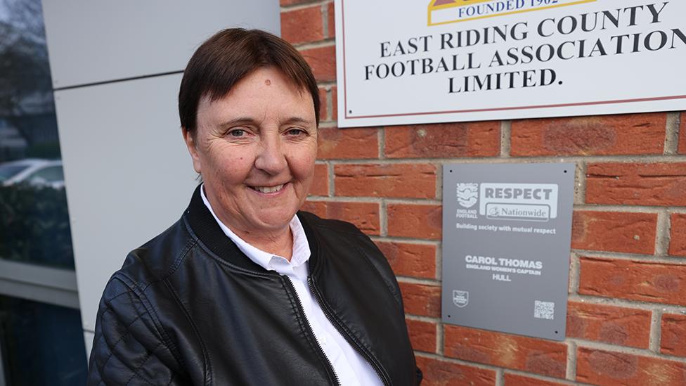 Carol Thomas in front of plaque