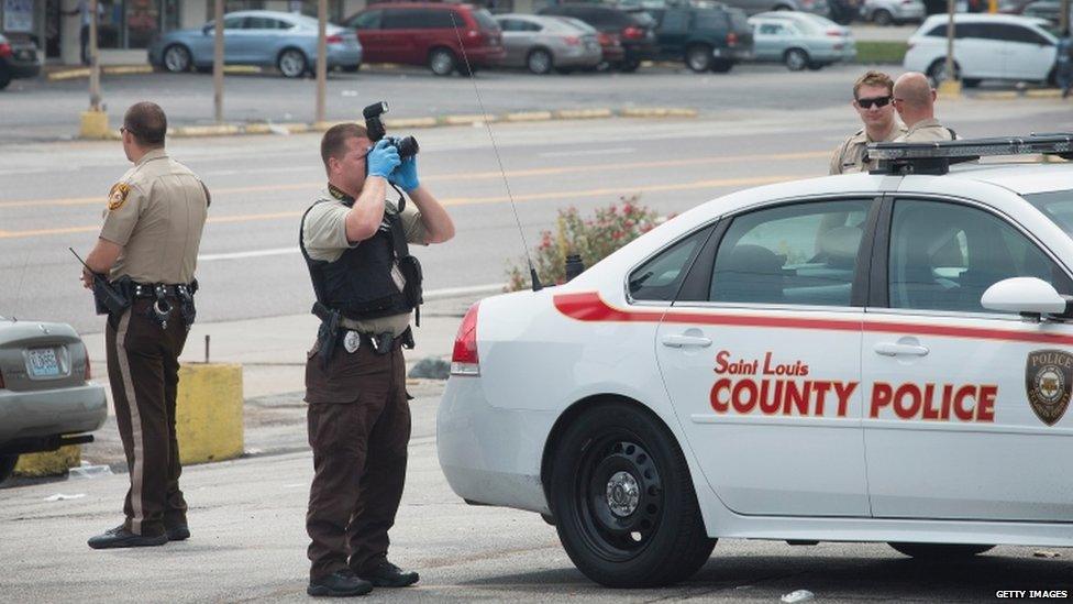 Police collect evidence the morning after looting broke out and gunfire erupted along West Florrisant Street during a demonstration to mark the first anniversary of the shooting of Michael Brown on 10 August 2015 in Ferguson, Missouri.