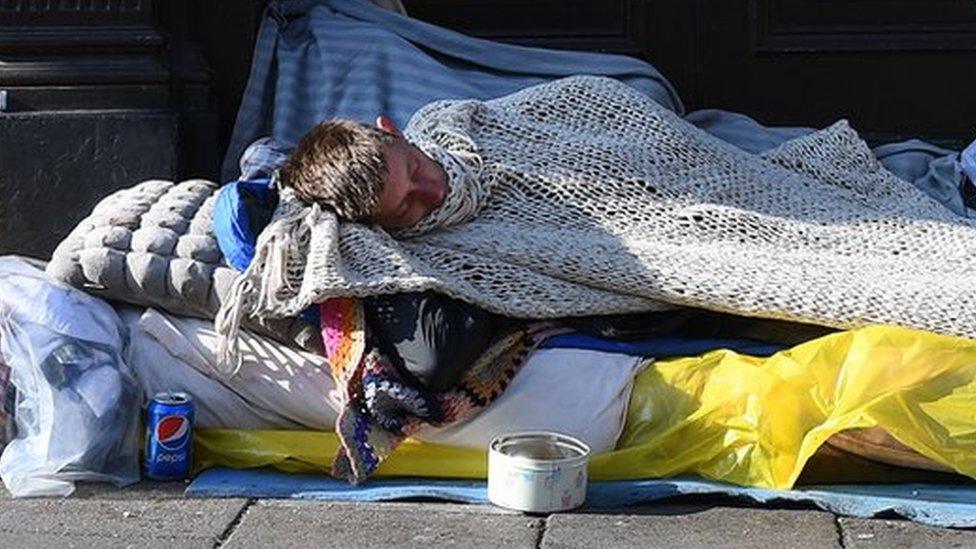 A woman walks past a rough sleeper