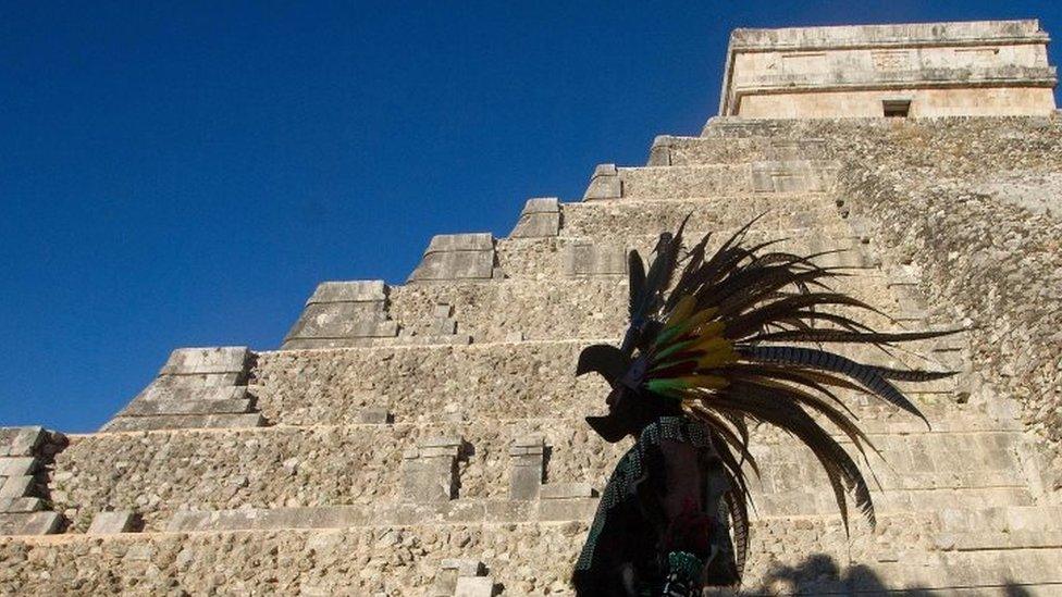 A Mexican man wearing a pre-hispanic costume walks next to the Kukulkan pyramid at the Chichen Itza archaeological park (20 December 2012)