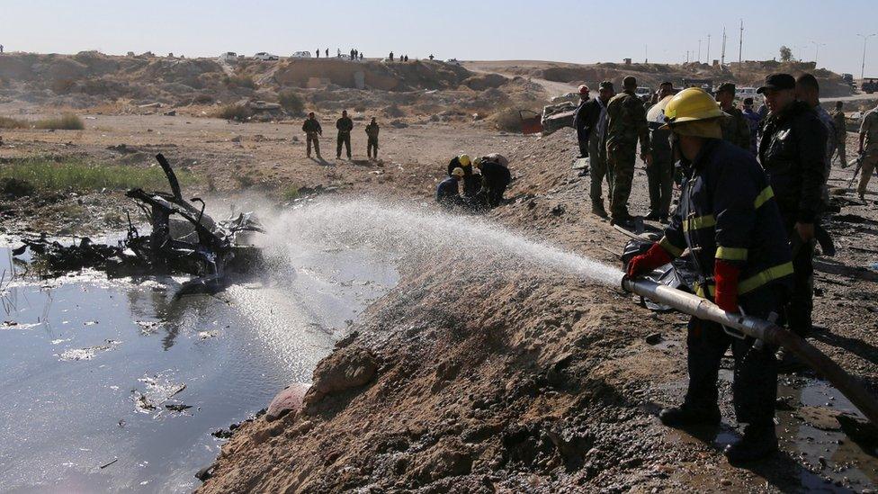 Firefighter hoses down remnants of suicide bomb blast near Tikrit on 6 November 2016