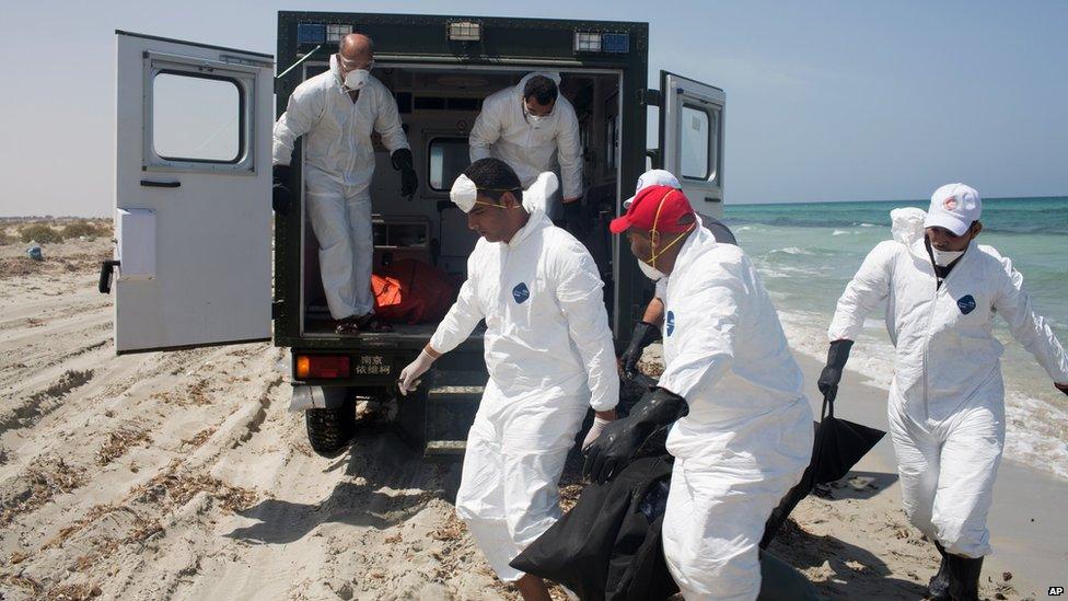 Workers for the Red Crescent carry the body of a dead migrant at the waterfront in Zuwara