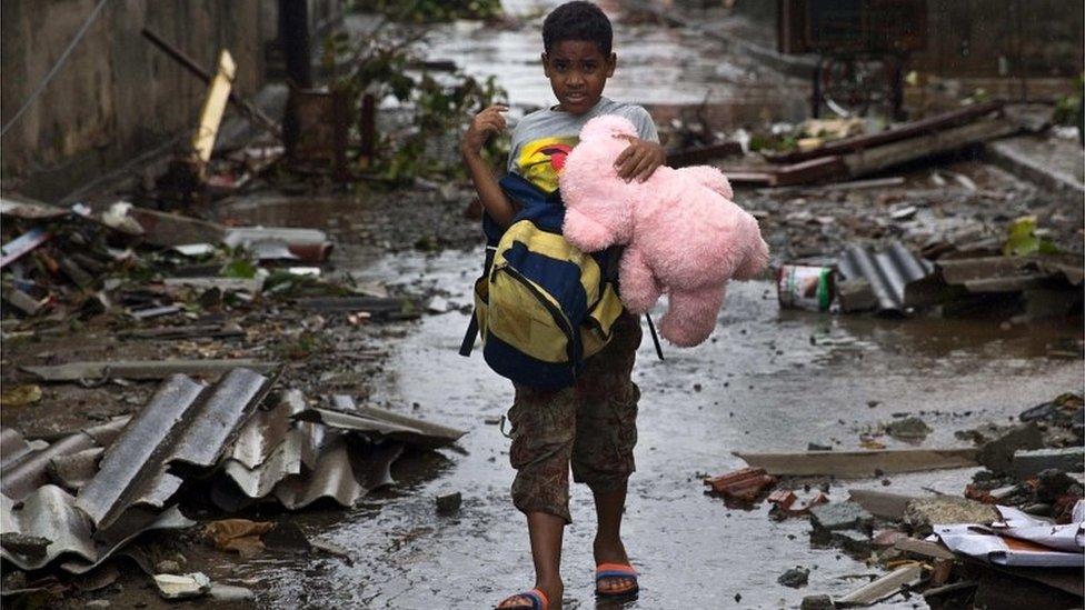 Boy carries his belongings through devastated Baracoa, Cuba, on 5 October 2016