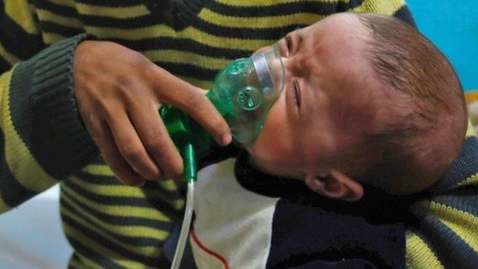 A Syrian boy holds an oxygen mask over the face of an infant at a make-shift hospital following a reported gas attack on the rebel-held besieged town of Douma in the eastern Ghouta region on the outskirts of the capital Damascus on January 22, 2018