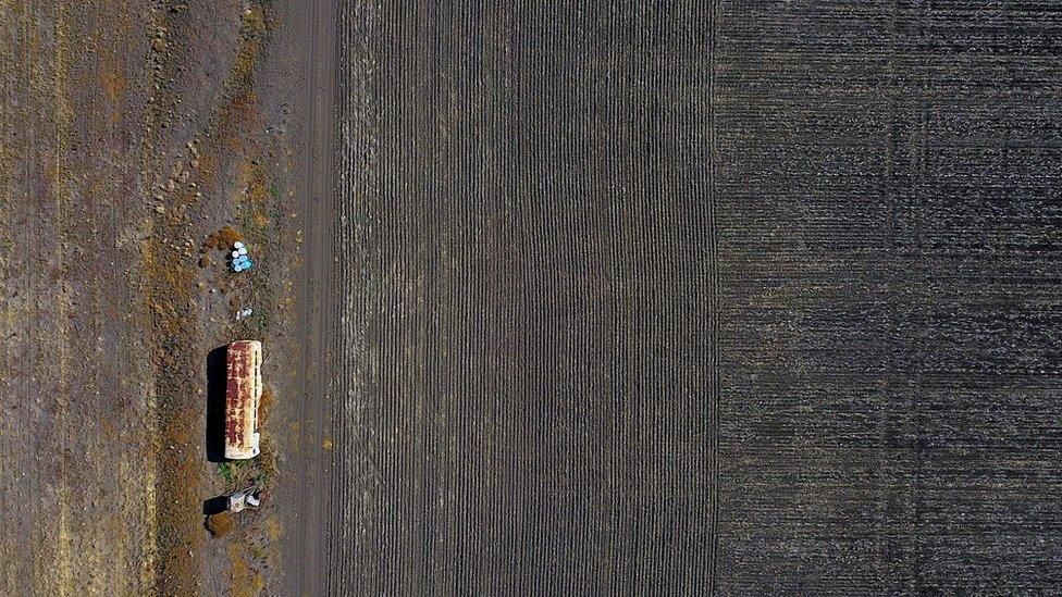 An old bus used for storing farming equipment stands in a drought-affected paddock on a property located west of the town of Gunnedah