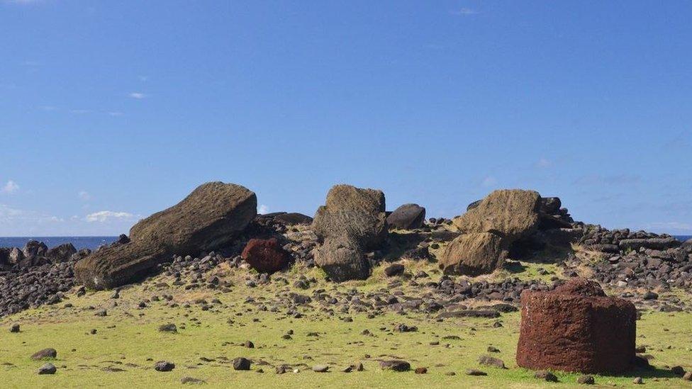 Red scoria pukao hat with tuff rock in background