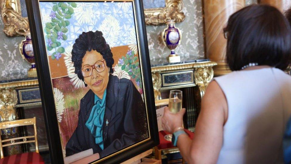 A woman looking at a portrait in Buckingham Palace