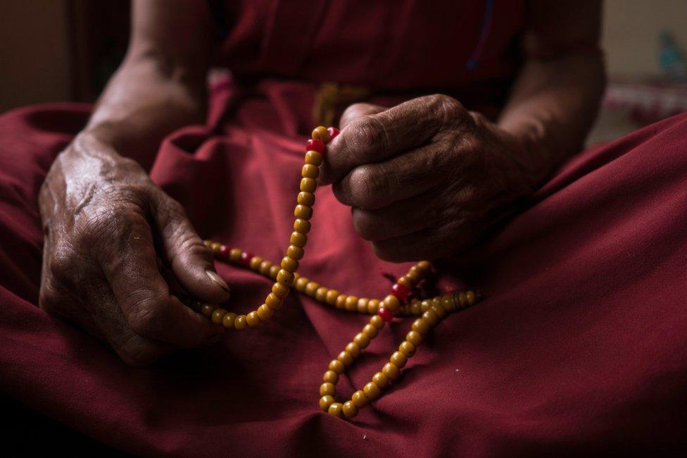 An elderly nun holds prayer beads