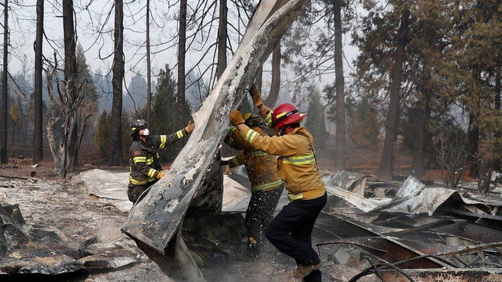 Firefighters move debris from an area affected by the Camp Fire, California (18 November)