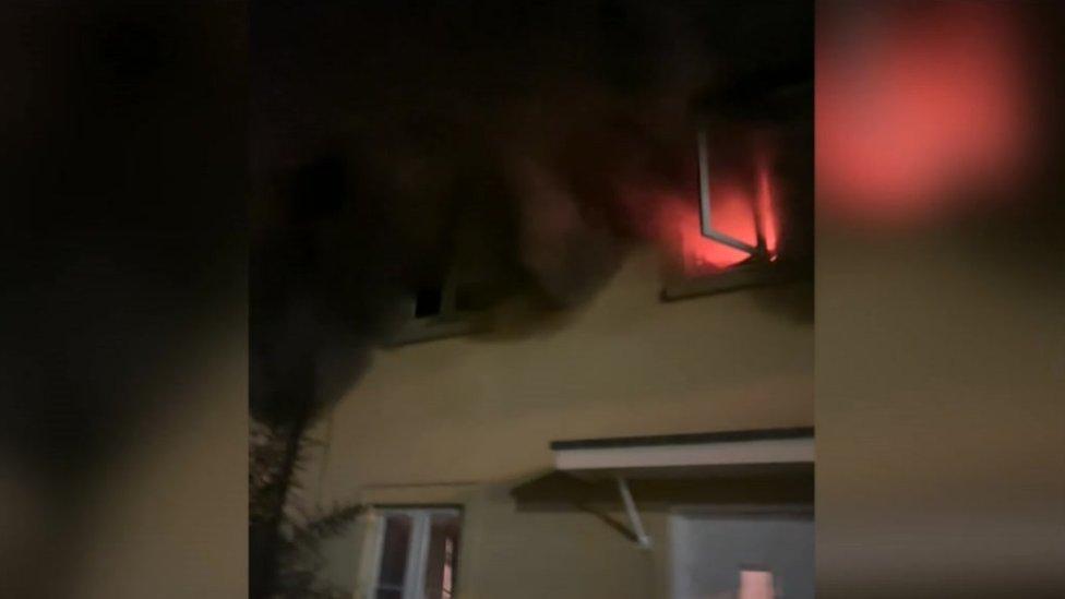 Flames and smoke coming out of window of house