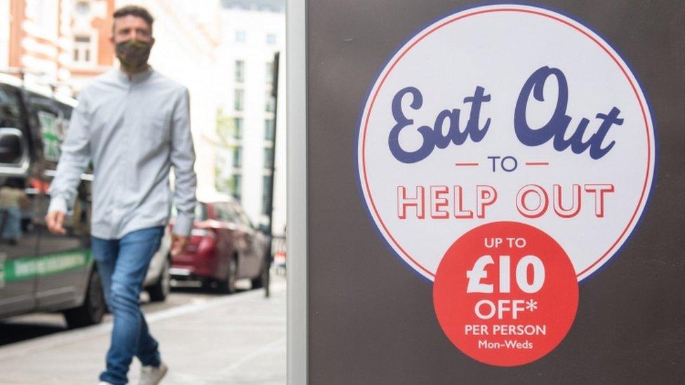 A poster for the Eat Out to Help Out scheme with someone walking in the background