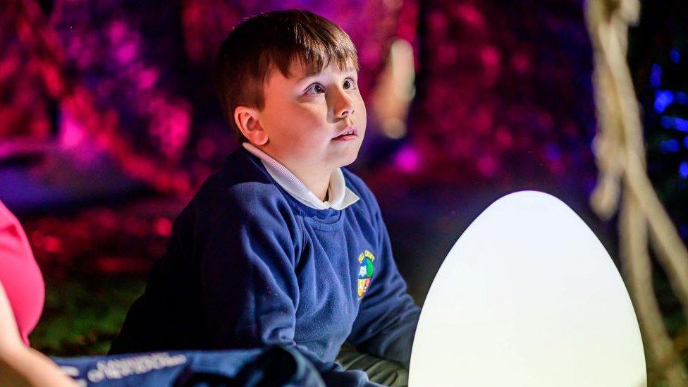 A child at the performance sits looking towards the show