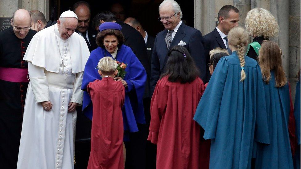 Queen Silvia of Sweden receives flowers from children flanked by Pope Francis and King Carl XVI Gustaf, outside the King's House in Lund, Sweden (31 Oct. 2016)