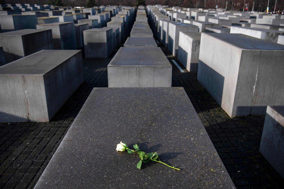 A rose lies on one of the concrete steles