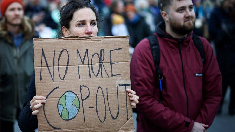 A protester holds up a sign saying 'no more COP-out'