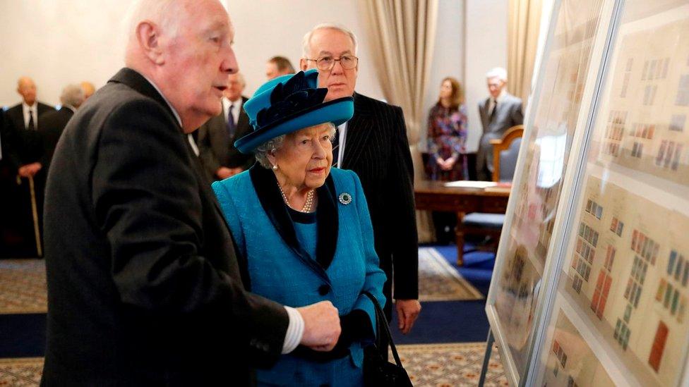 Britain's Queen Elizabeth II is shown stamps of previous British monarchs as she visits the new headquarters of the Royal Philatelic society