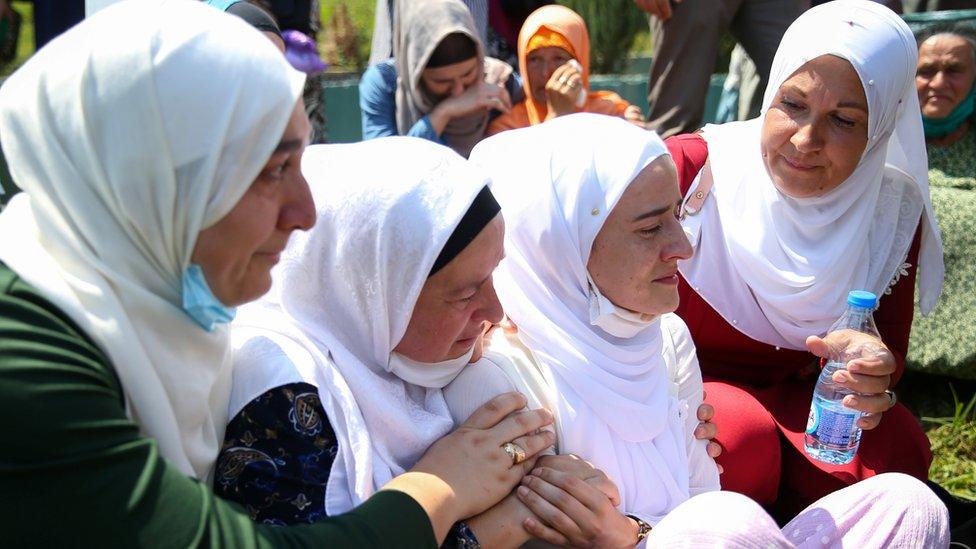 Women cry at a graveyard during a mass funeral in Potocari near Srebrenica