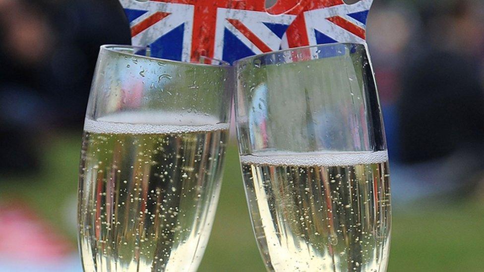 Two sparkling wine glasses with British flag "crowns" on top