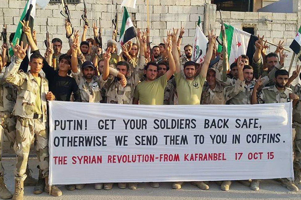 Free Syrian Army fighters of Fursan al-Haq Brigade hold a banner, in Kafranbel, Idlib province, northern Syria