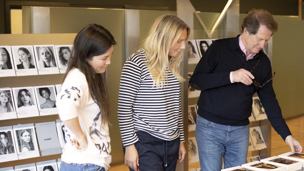 John Horner reviewing models' pictures alongside colleagues at his firm Models 1 ahead of London Fashion Week