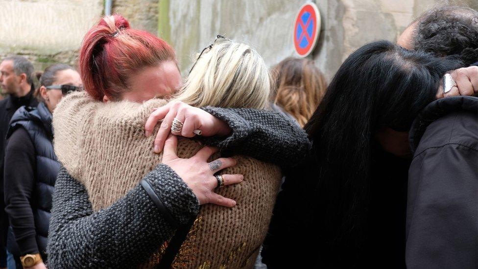 People console each other outside the Saint Etienne Church in Trebes in southwest France, after a service of remembrance to victims