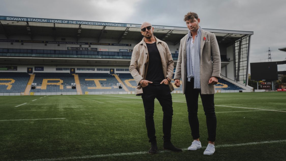 Two men standing on a rugby pitch