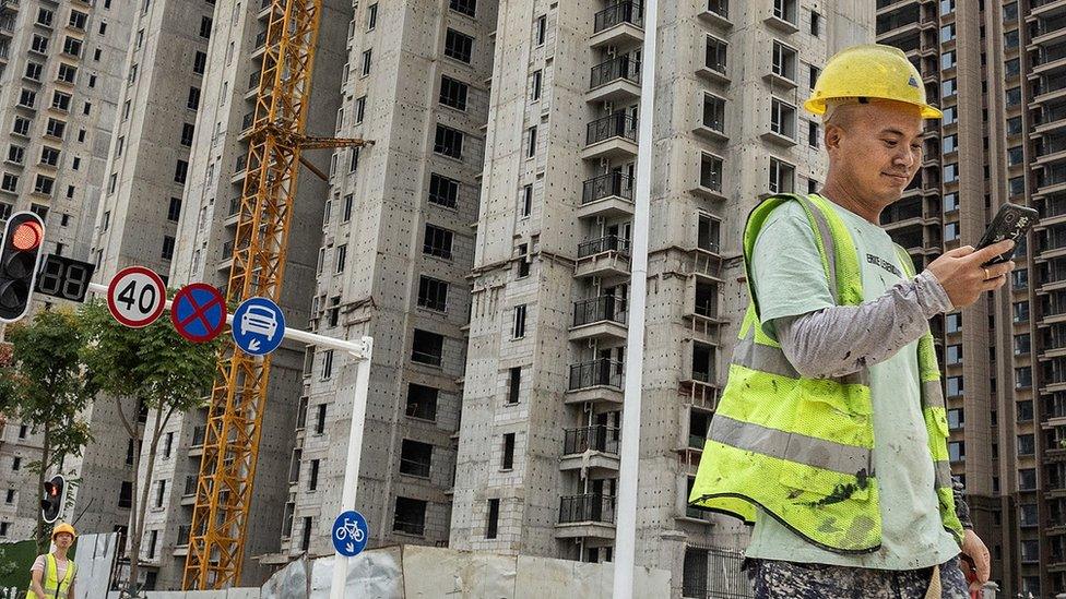 A worker walks past a housing complex under construction by Chinese property developer Evergrande in Wuhan, China on 28 September 2023.