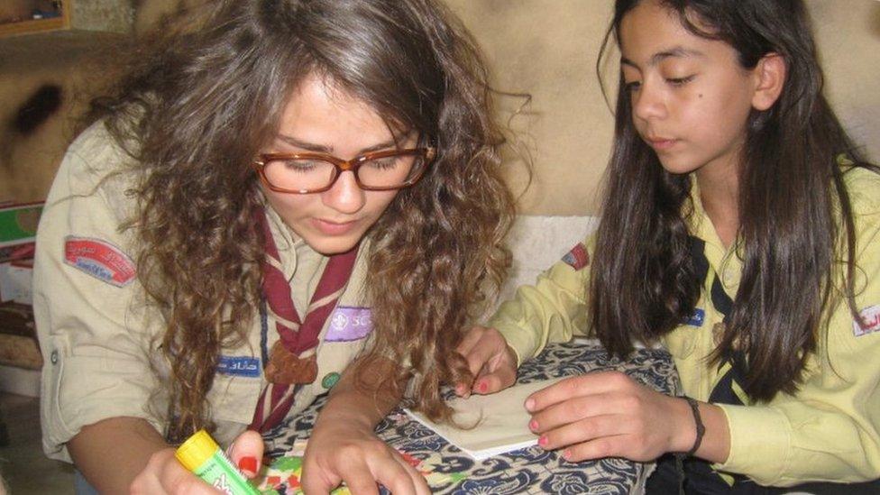 Sham doing arts and crafts with a younger member, both in uniform