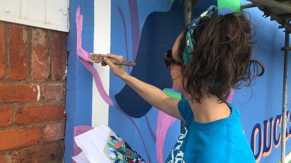 Zoe Power painting a mural