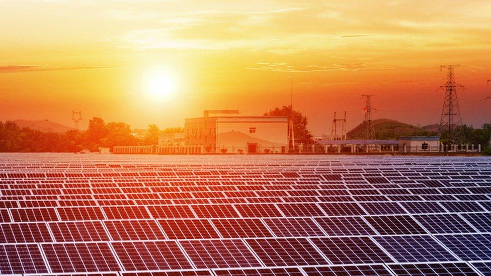 The Sun rises over rows over solar panels