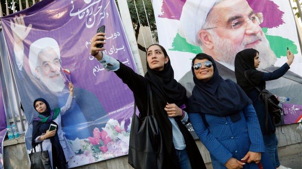 Women pose in front of posters of Hassan Rouhani in Tehran (09/05/17)