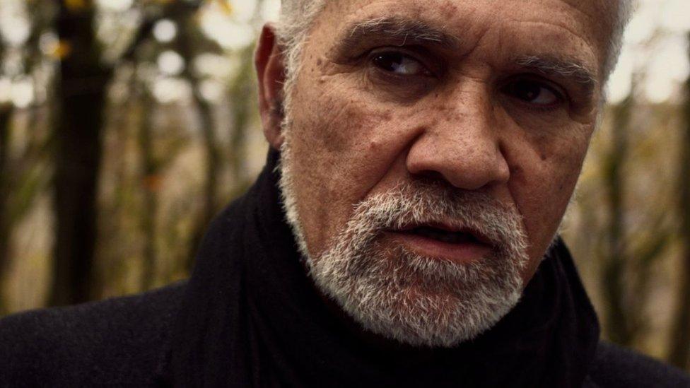 A close up of Ralph Hoyte looking away from the camera with white hair and beard