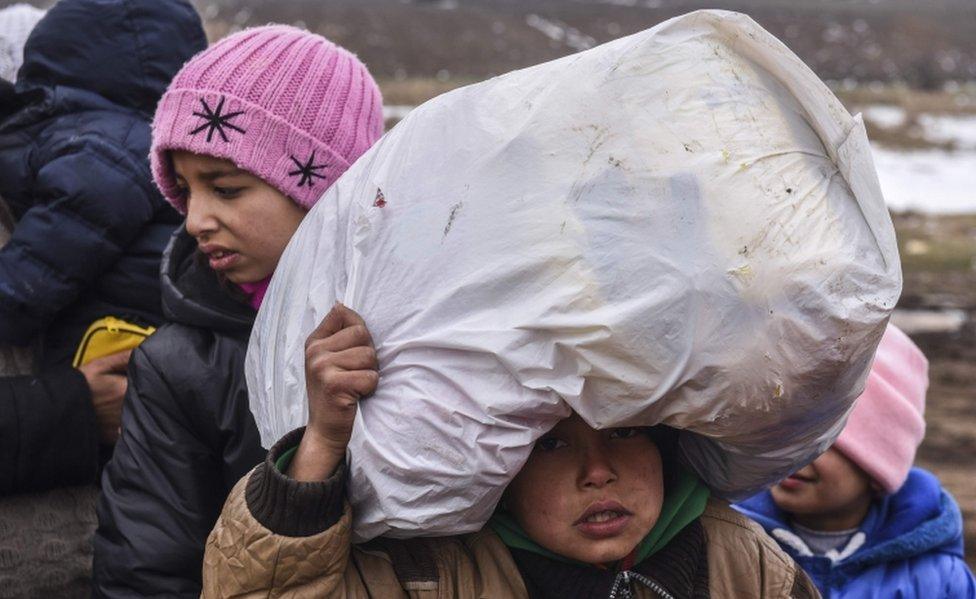 A child migrant holds his belongings as he waits on the Macedonian border into Serbia