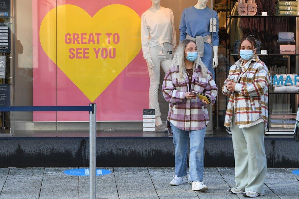 Two women wearing face masks stand outside Primark