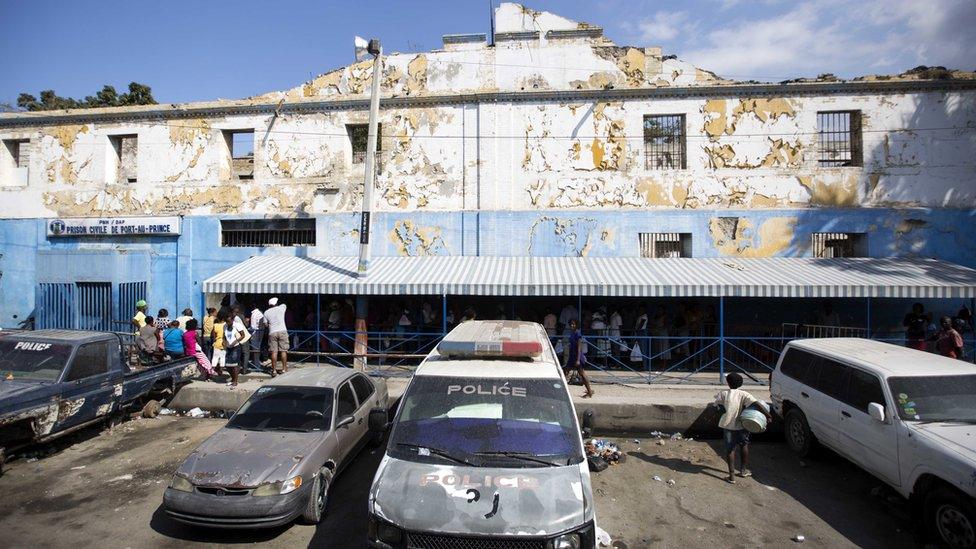 Families with food in tow for their incarcerated relatives, line up in front of the National Penitentiary in downtown Port-au-Prince