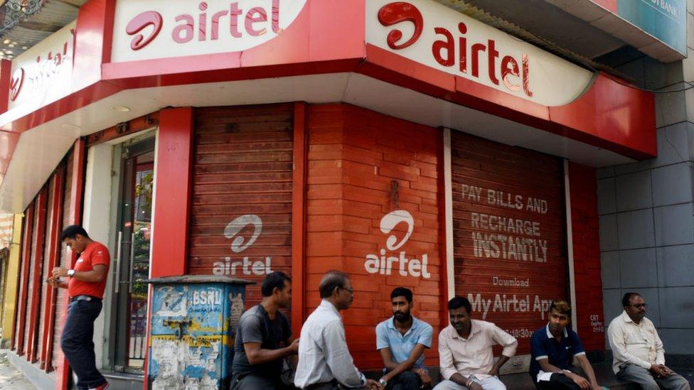 Men sit in front of Airtel store in Kolkata