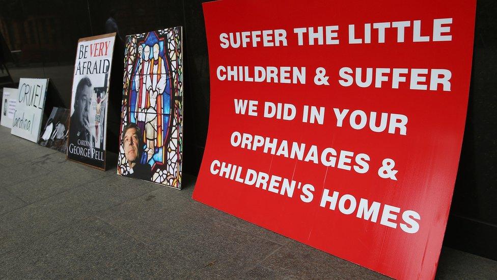 Protest signs criticising Cardinal Pell