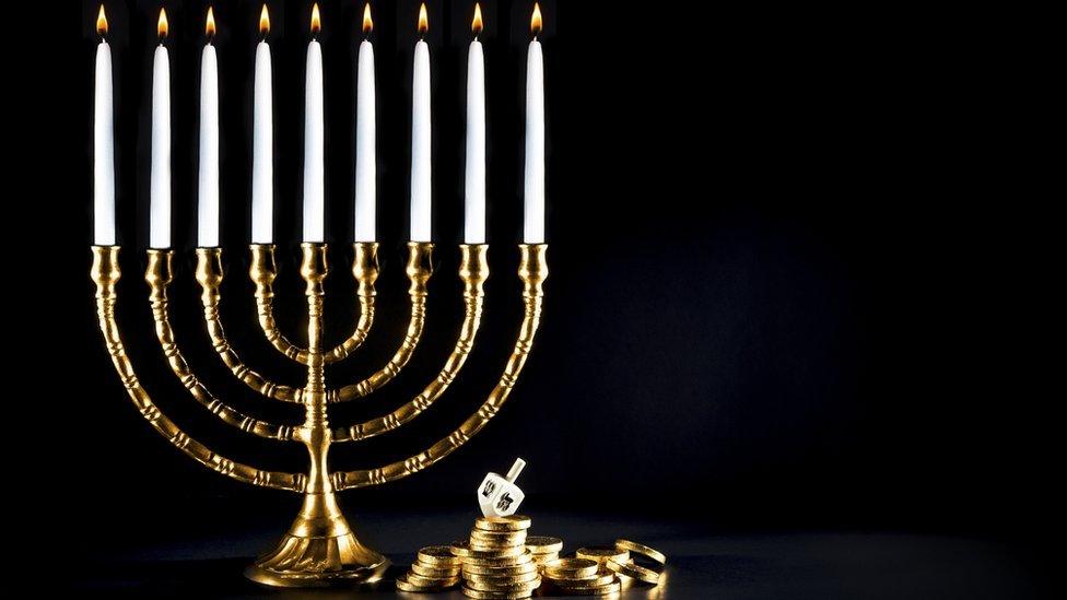 A golden menorah with dreidl and coins